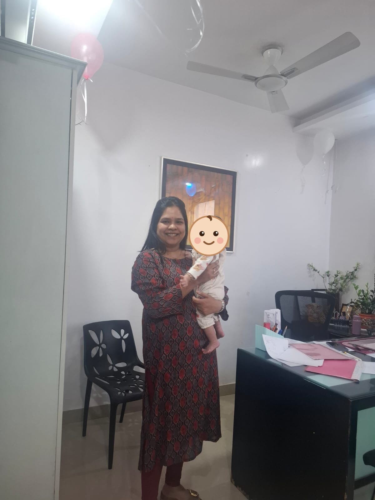 Dr. Vellala holding a baby among celebration balloons