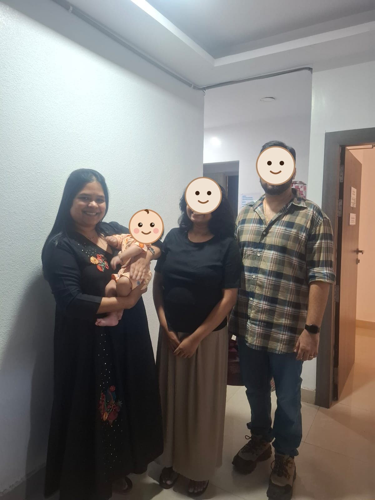 Dr. Vellala holding a newborn beside their parents at the clinic