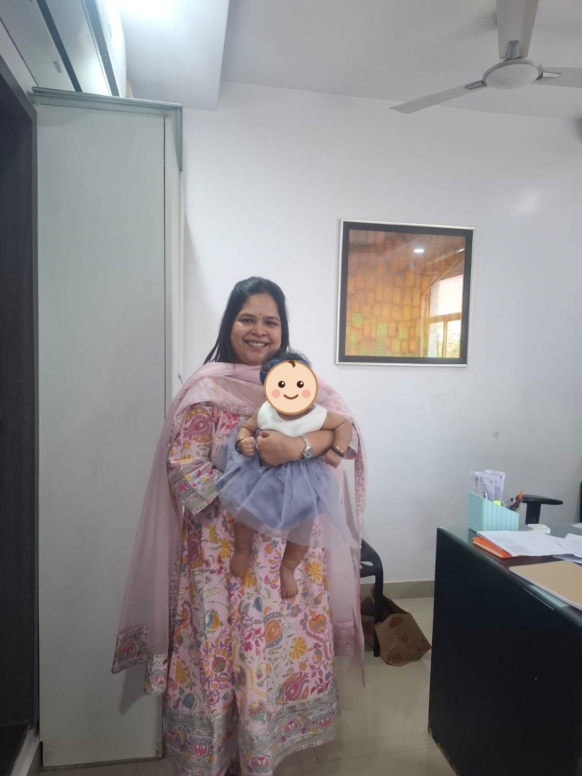 Dr. Vellala holding a baby in the consulting room