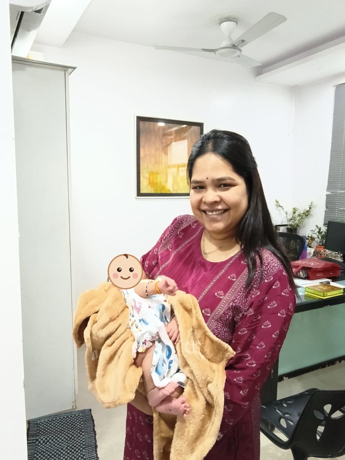 Dr. Vellala cradling a newborn wrapped in a blanket