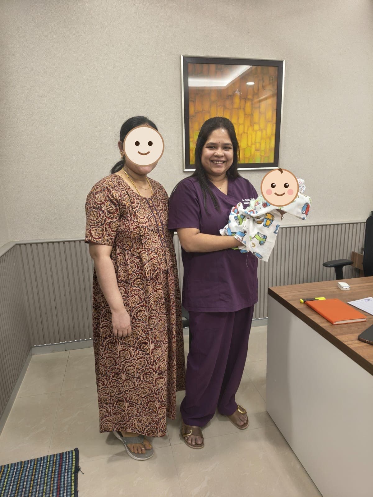 Dr. Vellala in scrubs with a newborn beside their mother
