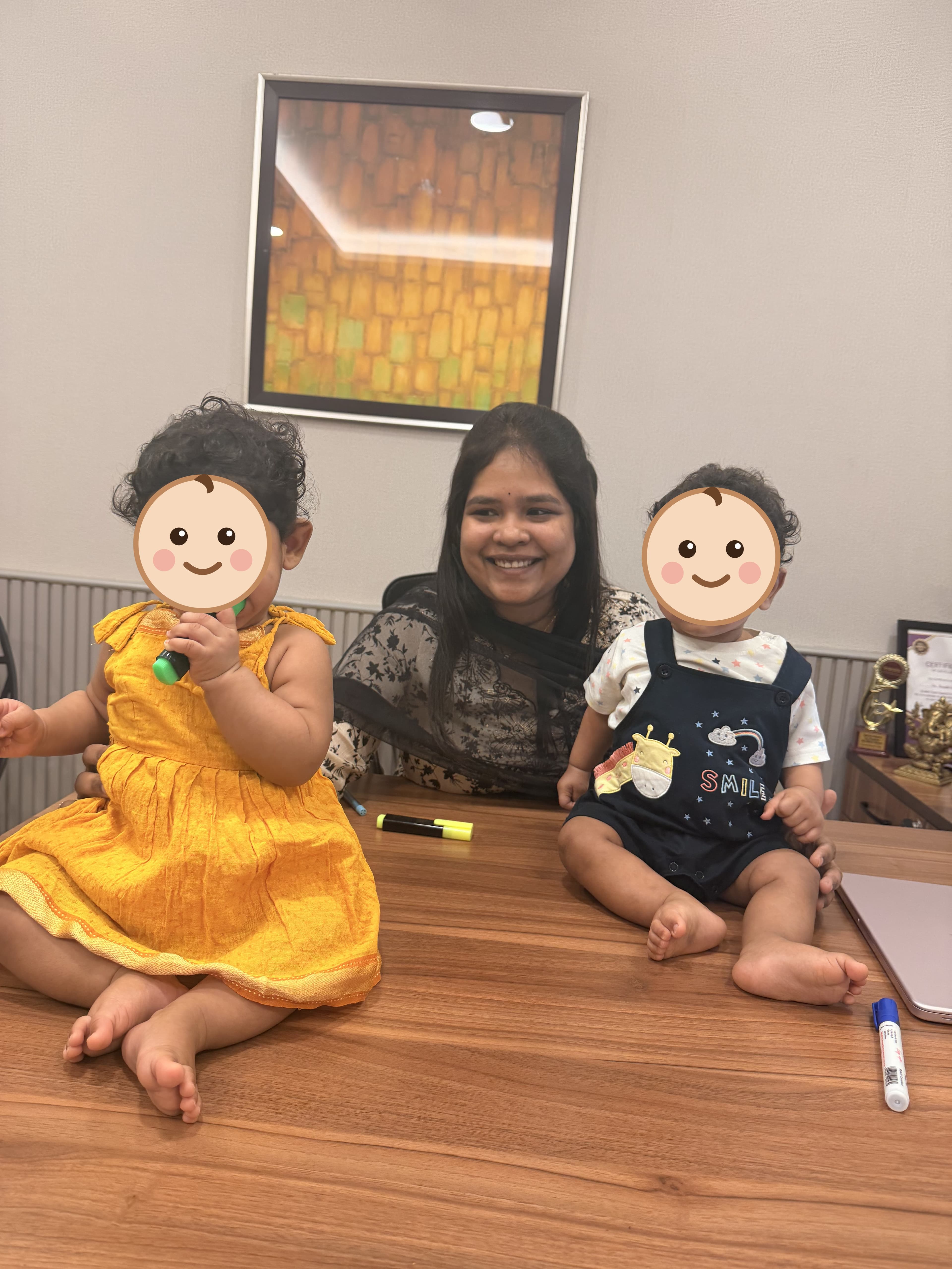 A mother with her twin toddlers at the clinic desk